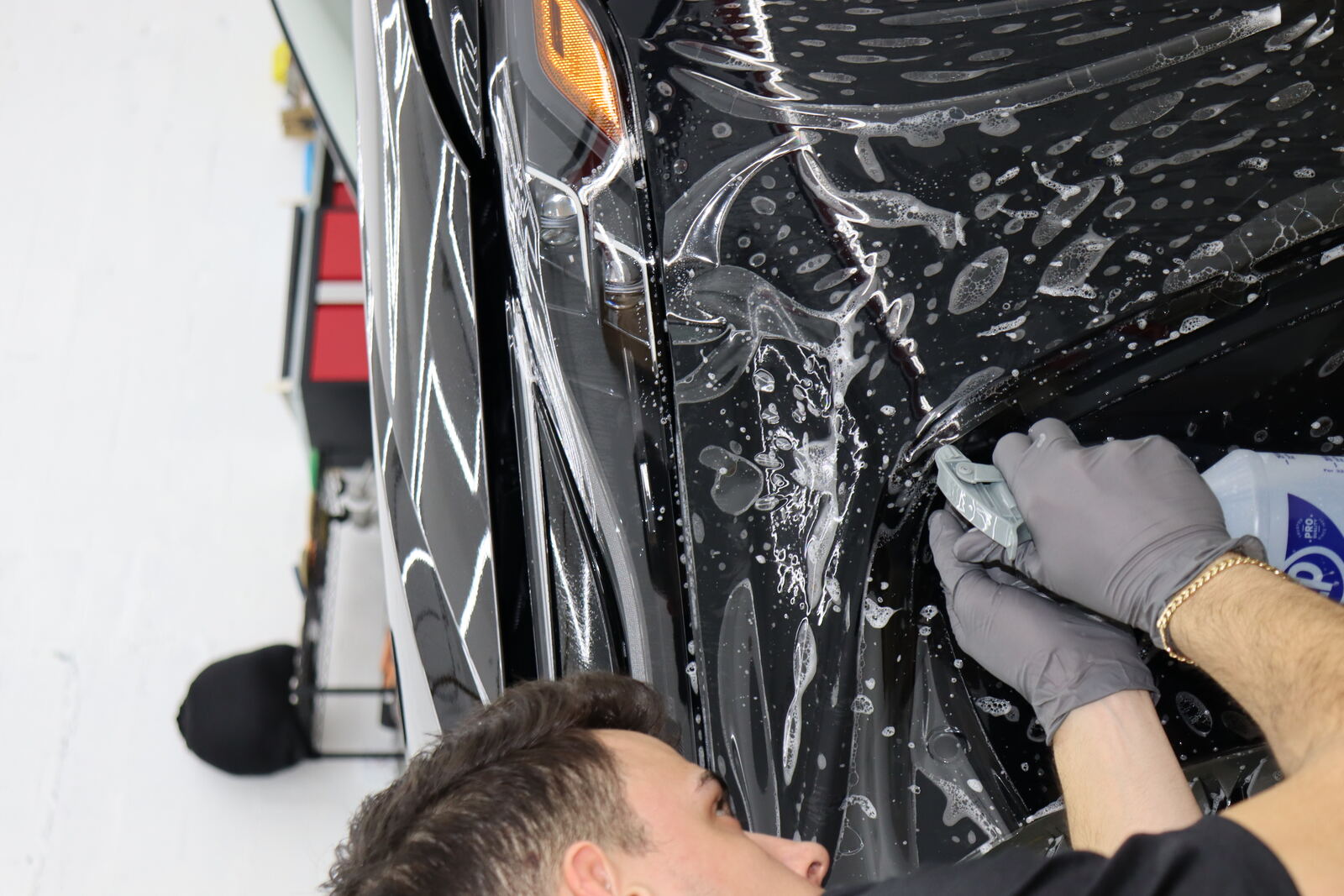 Installer squeegeeing paint protection film onto a panel
