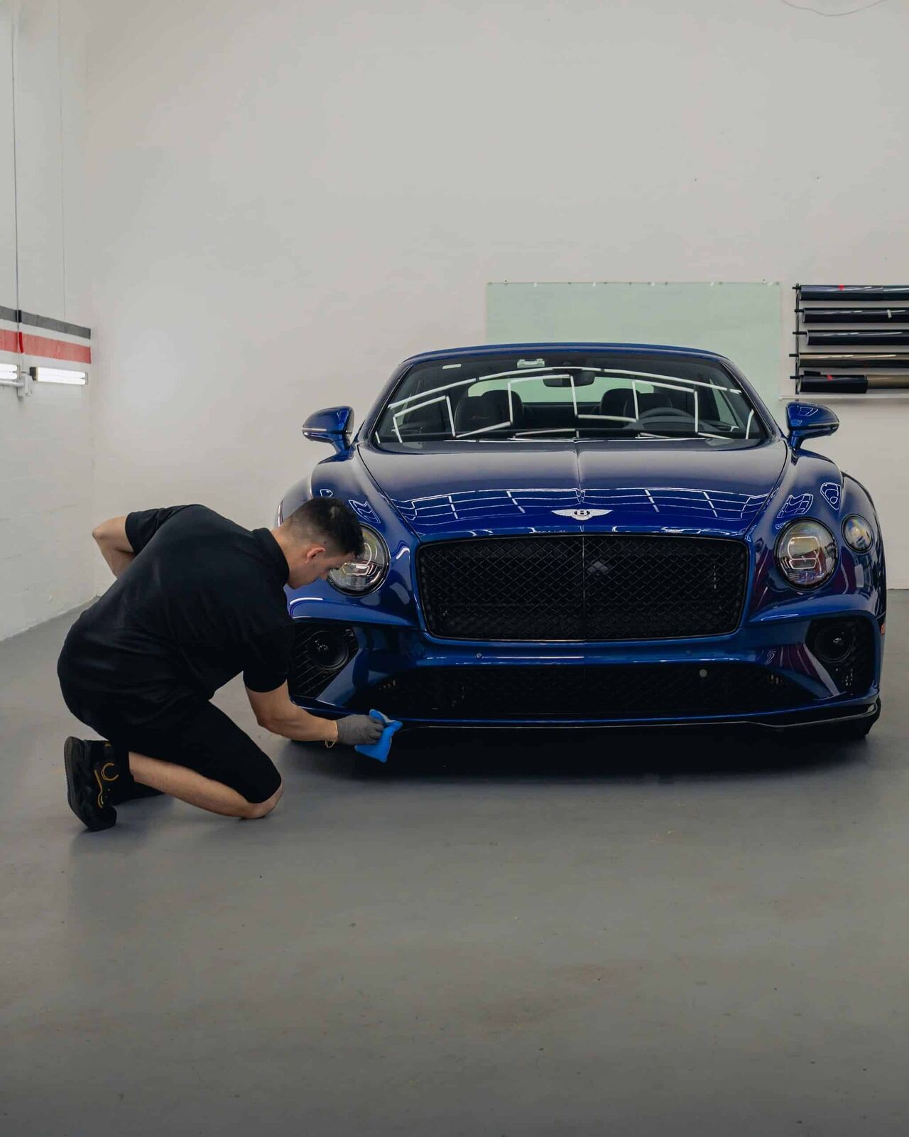 Technician working on a blue Bentley front end